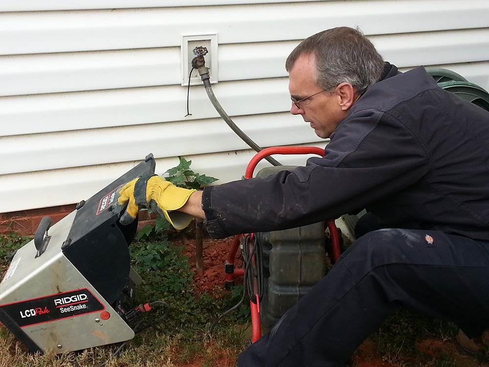 A plumber using a camera to look down a pipe